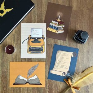 Postkaartenset met illustraties van een typemachine, boekenstapel met kaarslicht, open boek met veer en perkament met inkt van het merk Nouk-san